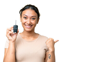 Young Uruguayan woman holding car keys over isolated chroma key background pointing to the side to...