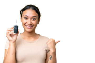 Young Uruguayan woman holding car keys over isolated chroma key background pointing to the side to present a product