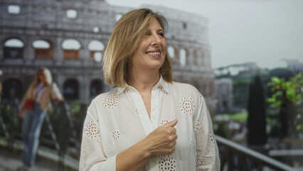 Fototapeta premium Woman in white eyelet blouse pointing finger at ancient coliseum ruins on sunny outdoor walkway near historic roman amphitheater; curiosity.