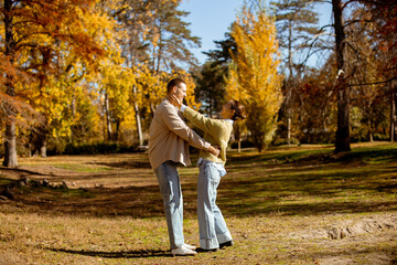 Fototapeta premium Joyful autumn day with a couple in a vibrant park full of falling leaves