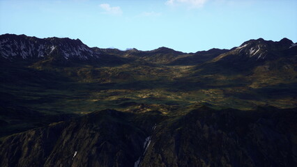 Majestic mountains stretch across the horizon, their peaks dusted with snow. A vibrant green valley lies below, illuminated by the soft glow of sunlight. The scene is tranquil and untouched.