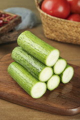 Fresh Loofah Vegetables from Shandong China Sliced on Wooden Board with Tomatoes in Kitchen