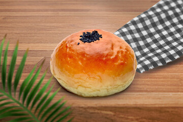 Freshly Baked Golden Sweet Bun with Black Sesame Seeds on Wooden Table