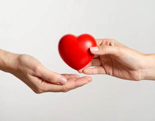 Obraz premium Close-up image of two hands gently passing a red heart-shaped stress ball, symbolizing compassion, blood donation, and the act of sharing life.