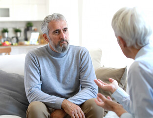 Obraz premium Portrait of a senior mature or mid aged man looking thoughtful or stressed and sad while sitting in session with his female therapist