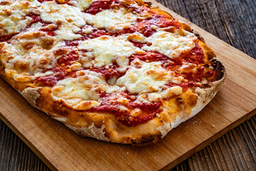 Pinsa Margherita with tomato sauce and mozzarella cheese on wooden background