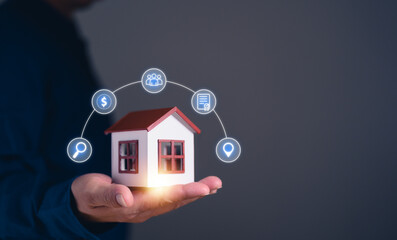 hand holding a house model with digital icons representing real estate investment, home insurance,...