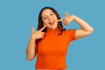 Young woman smiling pointing to her happy teeth