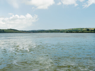 Rolling green hills line the distant shore.