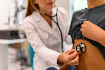 Midsection of female doctor using stethoscope on boy chest checking heart and lungs during medical checkup at clinic © Moon Safari