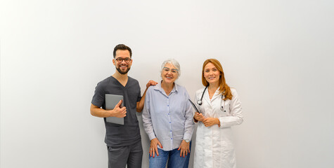 Portrait of smiling doctors with senior woman standing together against white background in hospital