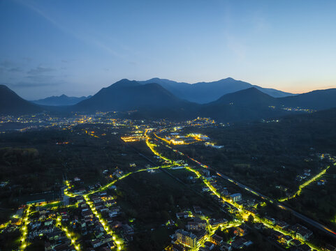 Aerial view of the town nestled amid rolling hills, lights twinkling like stars against the dark canvas of dusk, Santo Stefano del Sole, Irpinia, Campania, Italy.