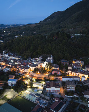 Aerial view of the town nestled beneath the shadowy mountain, lights glowing warmly against the deepening twilight, Santo Stefano del Sole, Irpinia, Italy.