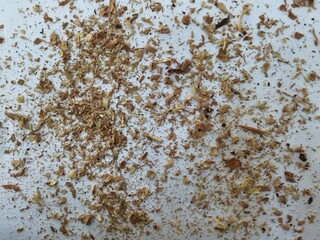 Scattered wooden dust particles on white surface showing natural texture and carpentry residue