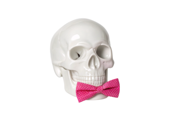 White porcelain skull with hollow eyes wearing pink polka dot patterned bow tie, isolated on a transparent background