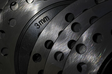 Close up detail of stacked metal brake disc with brushed steel texture. industrial machine part shows precise 3mm thickness marking, emphasizing high performance engineering