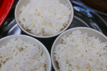 Close up top view of three simple white bowl of fluffy cooked rice. warm steam food portion of basic grain meal ready to eat, representing comforting and traditional diet