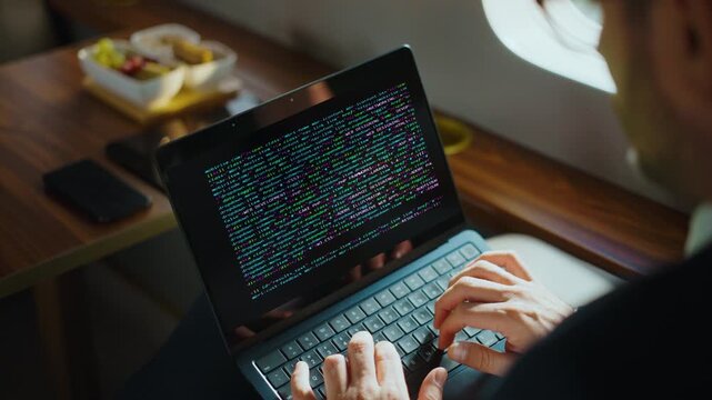 Unrecognized businessman typing on a laptop computer while sitting inside a private jet, a professional developer working with html code and programming during his business travel