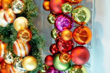 Vibrant Christmas baubles in red, gold, green, and pink hues drape over a pine garland, delivering a lively festive mood perfect for holiday decor and seasonal marketing visuals.