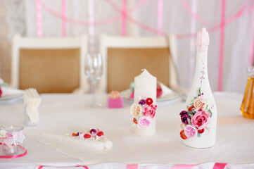 Softly lit celebration table featuring pink floral bottles, candles, and delicate decorations. Romantic, elegant ambiance perfect for weddings, parties, and intimate gatherings.