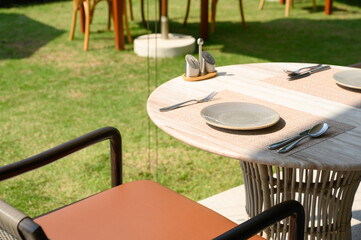 white dish with stainless steel spoon, knife, and fork on plate mat setting on the restaurant outdoor table.