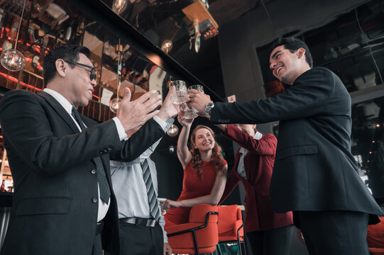 Group of diverse business professionals celebrating success and teamwork with a cheerful toast in a modern office lounge. Concept of achievement, partnership, and corporate happiness.