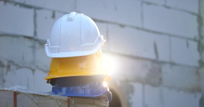 White, yellow, blue safety helmets on a pile of bricks in a construction site with beautiful sunlight.