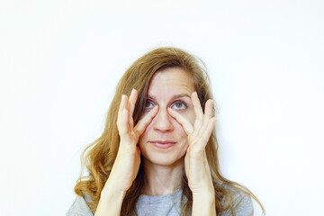 A woman massages the skin around her eyes with gentle finger movements. Symbolizes anti-aging skincare routine, dark circle reduction technique, eye bag treatment, and puffiness relief practice.