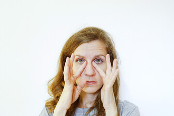 A woman massaging the under-eye area with her fingers. Symbolizes crow’s feet prevention exercise, tear trough smoothing technique, fine line reduction ritual, self care, and gentle facial massage.