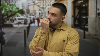 Man gestures with outstretched hand on urban street as he touches his forehead in discomfort; stress.