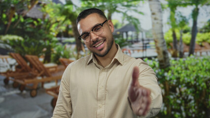 Man extends hand forward offering handshake in forest clearing under bright sunlight beside wooden bench  welcoming greeting. © Krakenimages.com