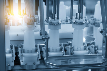 The empty healthcare bottles on the conveyor belt for filling process in blue tone scene with lighting effect.
