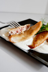 Golden fried empanadas filled with ham and cheese rest on a bed of creamy sauce and crisp greens. A tasty, shareable dish ideal for casual dining and appetizers.