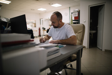 Man filling out paperwork at his desk in a workshop