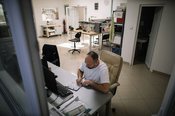 Technician completing documents at workbench in industrial workspace