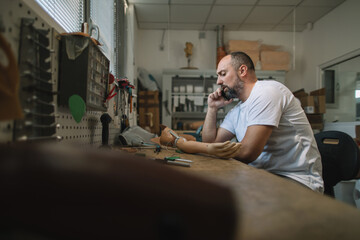 Orthopedic prosthetist talking on the phone at his workshop