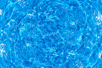 Blue water with ripples on the surface. Defocus blurred transparent blue colored clear calm water surface texture with splashes and bubbles. Water waves with shining pattern texture background.