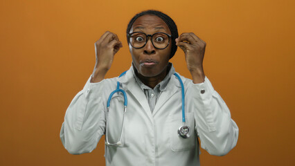 Woman doctor wearing white coat and stethoscope with expressive face against orange background, displaying curiosity and engagement, highlighting medical professionalism.