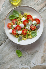 Plate with italian chicche di patate served in caprese style, vertical shot on a grey granite background with space, flat lay