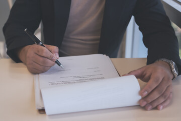 Businessman reviewing and signing official documents at a desk, representing contract approval, legal agreement, paperwork, business negotiation, and professional responsibility.