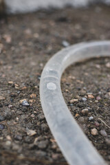 A transparent hose filled with water lies on the ground. High quality photo