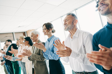 Obraz premium Diverse group of business professionals clapping together at a corporate meeting in a modern office setting