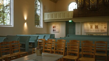 Blurred interior of a lutheran chapel featuring wooden chairs, pale green pews, and a defocused...