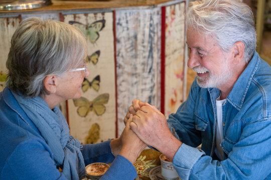 Happy senior couple enjoying coffee together at a cozy café sharing pleasant conversation. The atmosphere is relaxed and intimate, symbolizing love, companionship, and joyful aging.