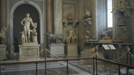 Soft bokeh of marble sculptures on pedestals and rope barrier in a defocused museum; background backplate copyspace calm.