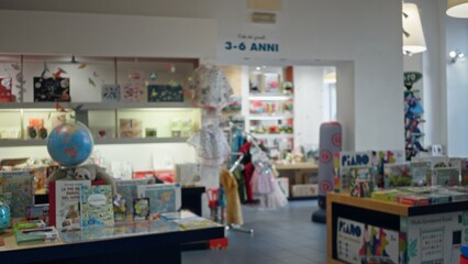 Blurred toy shop interior with shallow bokeh showing defocused shelves, displays, books and toys in an indoor retail space; background backdrop copyspace.