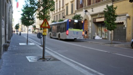 Blurred urban scene with shallow bokeh showing a passing bus, trees and sidewalk on a street; background backplate copyspace calm.