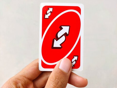 Malang, Indonesia - November 02, 2025: Red reverse card of the Uno card held by a hand. 