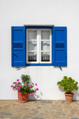 Window with blue shutters of a typical Greek house in Aegiali village on the island of Amorgos. Cyclades, Greece