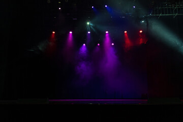 An empty stage of the theater, lit by spotlights and smoke before the performance